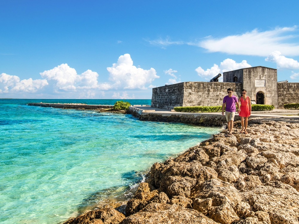 A couple walking hand-in-hand along the rocks at Fort Montague, Bahamas.