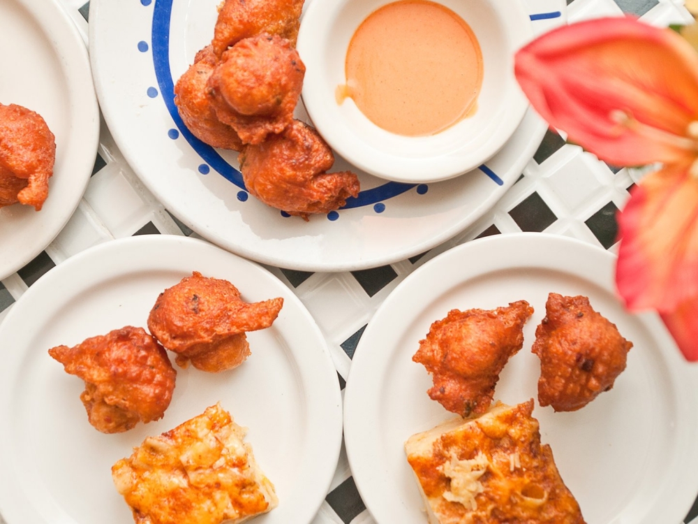 Fritters set atop white plates with an orange flower.