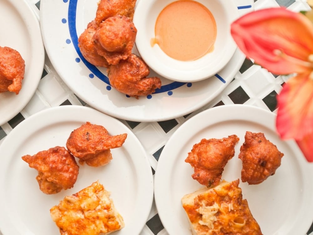 Bahamian Conch fritters set atop white plates.