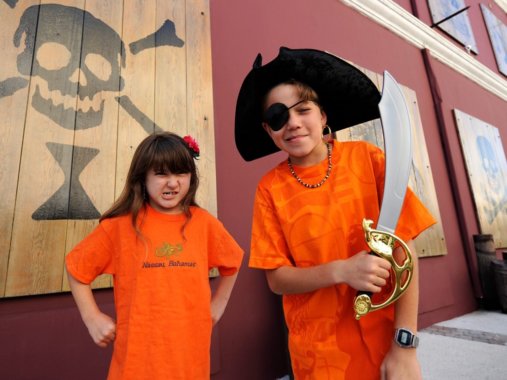 A young girl and a young boy wearing pirate swag outside of the Pirate Museum.