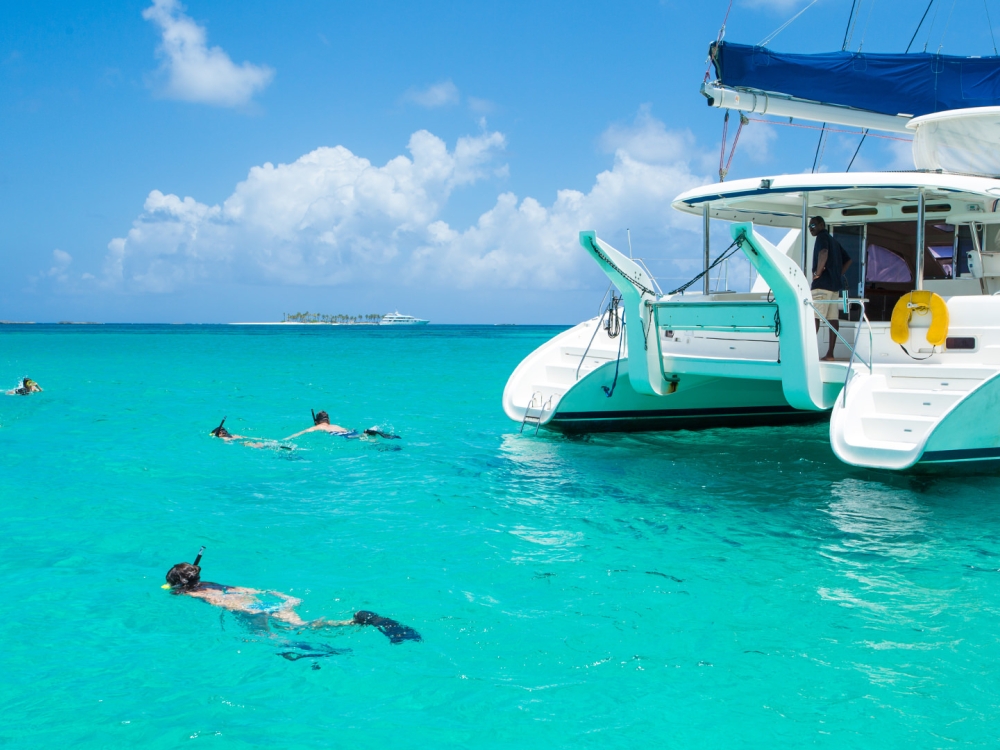 A group of people snorkelling around a catamaran.