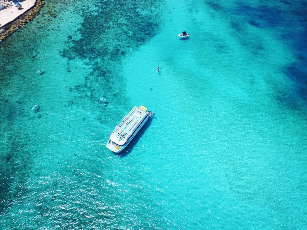 An aerial view of boats in crystal clear tropical waters.