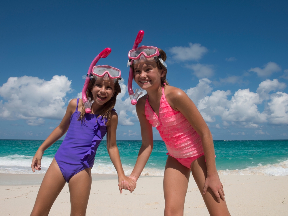Two kids standing on the beach in snorkel gear