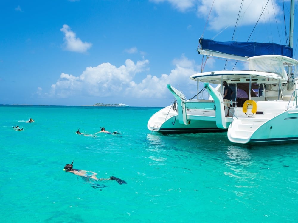 A family of four snorkel near a catamaran in Nassau Paradise Island.