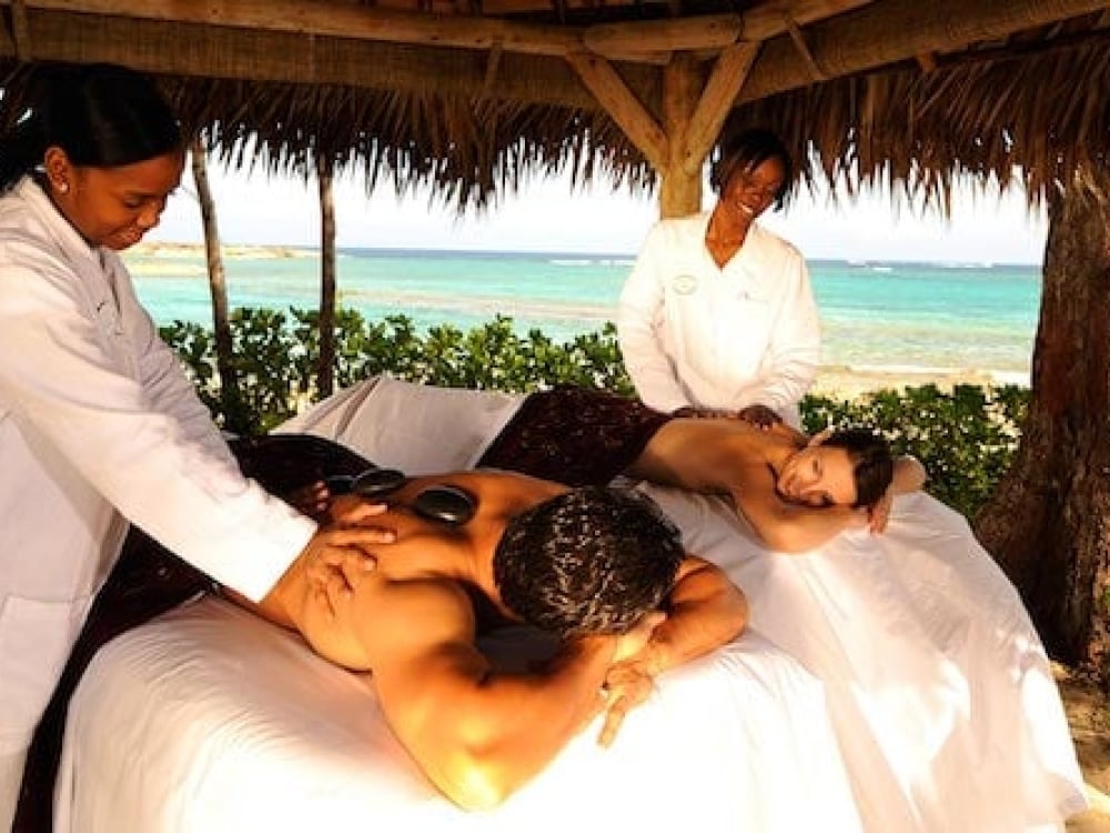 A man and woman enjoy a couples massage on the beach in The Bahamas. 