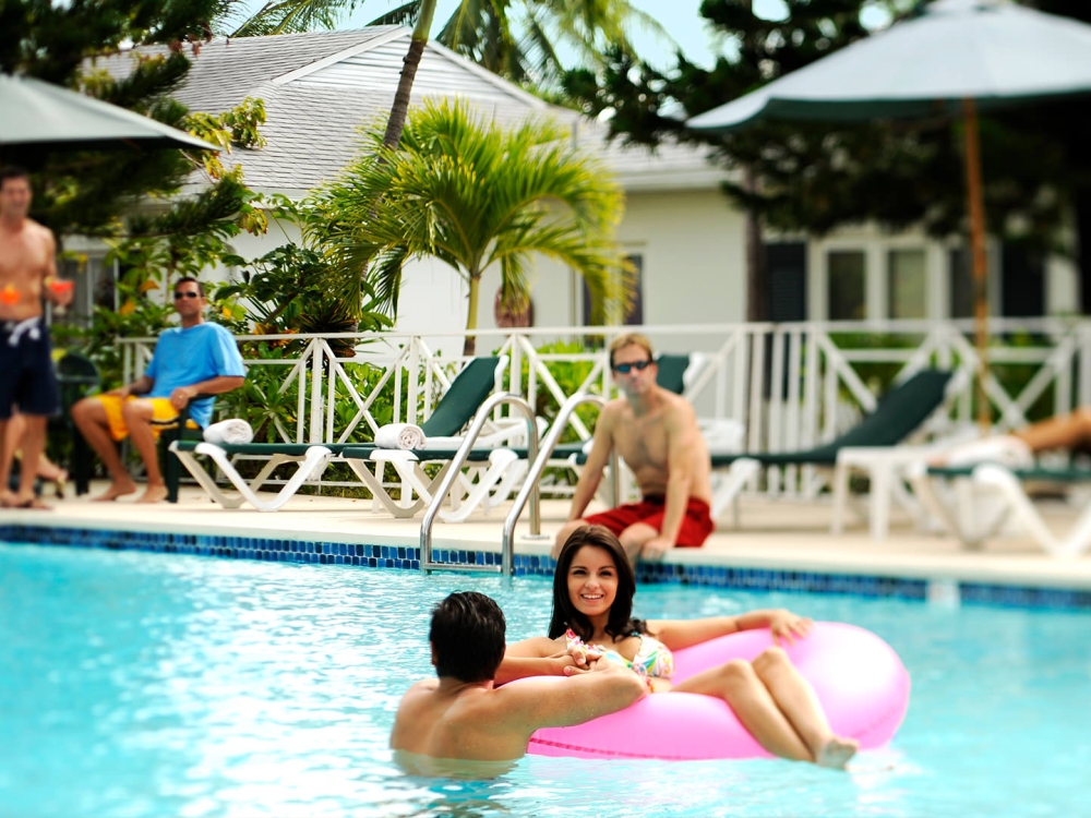 Groups of young people relax in and around a resort pool.