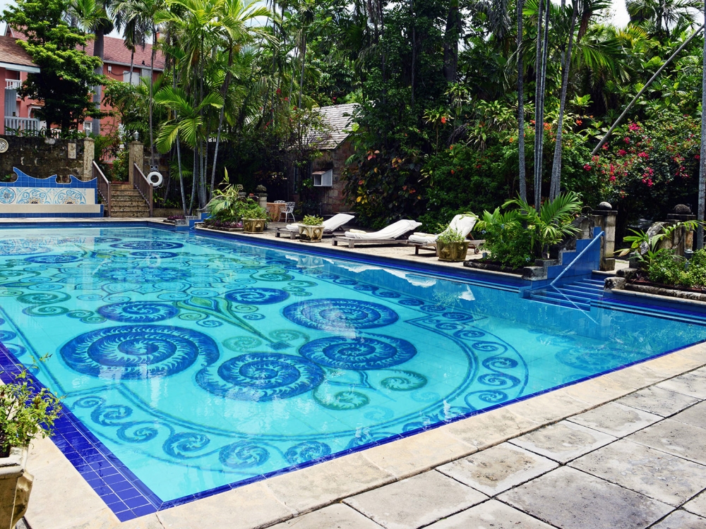 A pool with intricate details surrounded by green trees.