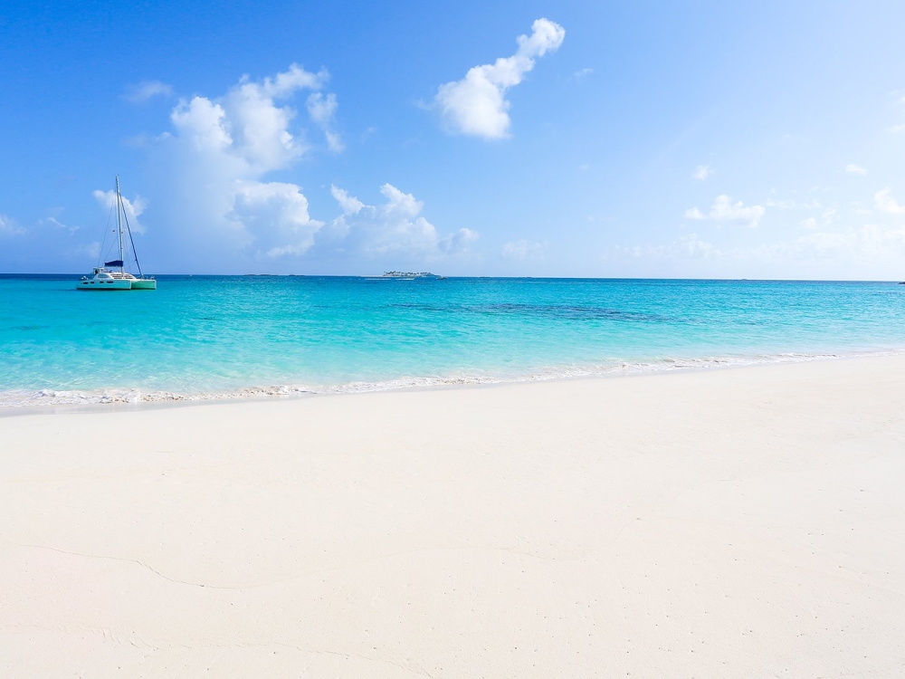 Sandy beach with blue water and boat in the ocean