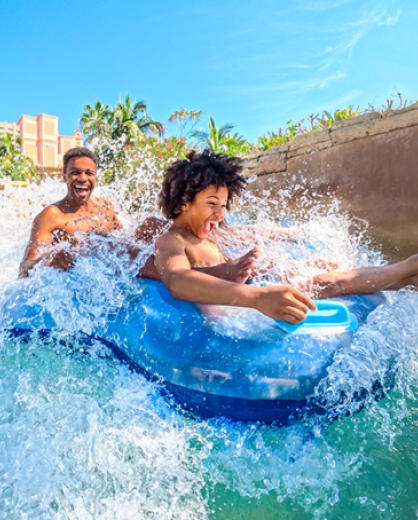 Two kids on a dual-person water float going down a water slide