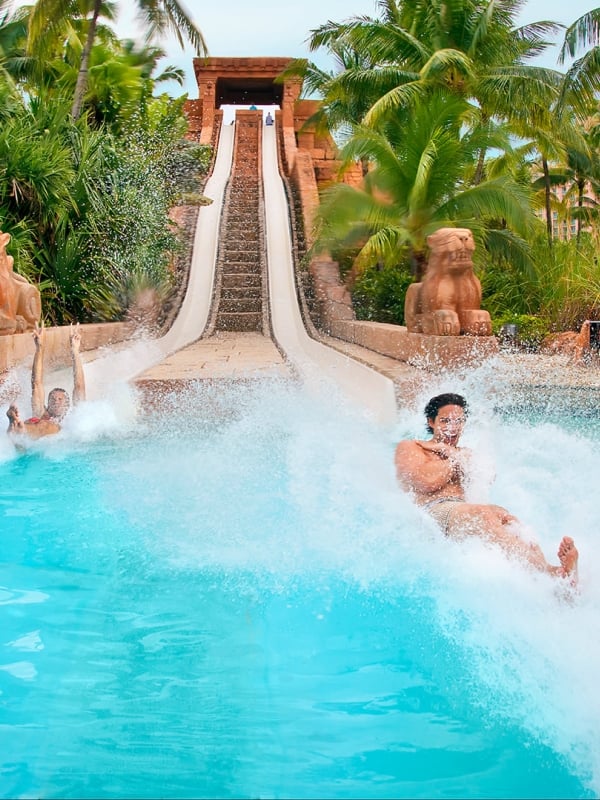 A couple sliding down a waterslide at Atlantis, Paradise Island