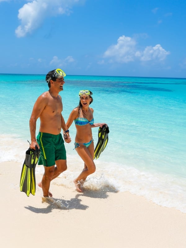 A couple with snorkel gear on the beach in Nassau Paradise Island