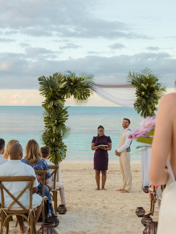 bride walking down the aisle towards groom at a beach wdding