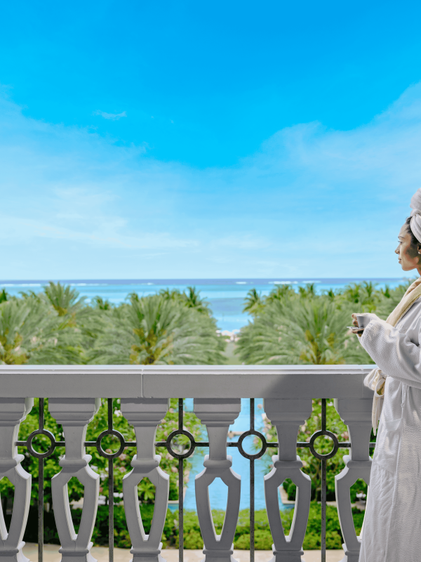 woman in robe looking out at the ocean from hotel 