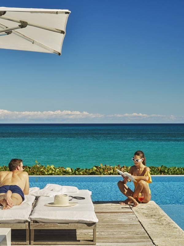couple lounging by a pool next to the ocean