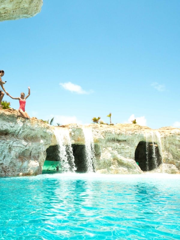 people jumping off a rock into water 