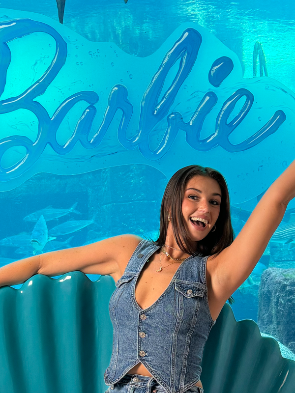 girl stading outside of a barbie sign