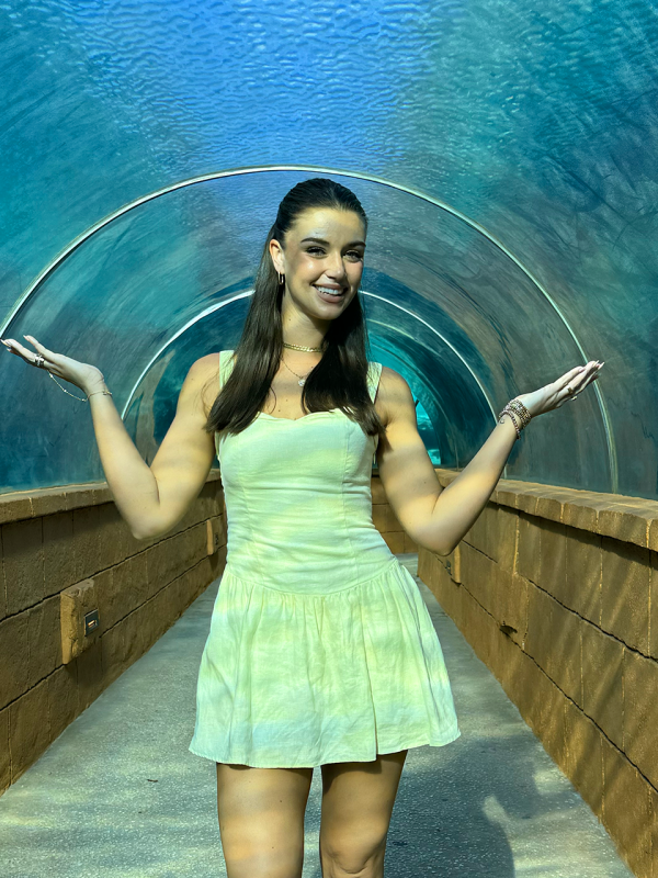 A woman stands in an underwater tunnel.