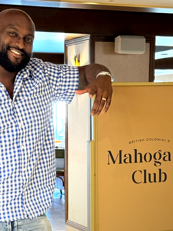 A man in a collared shirt leans on a box.