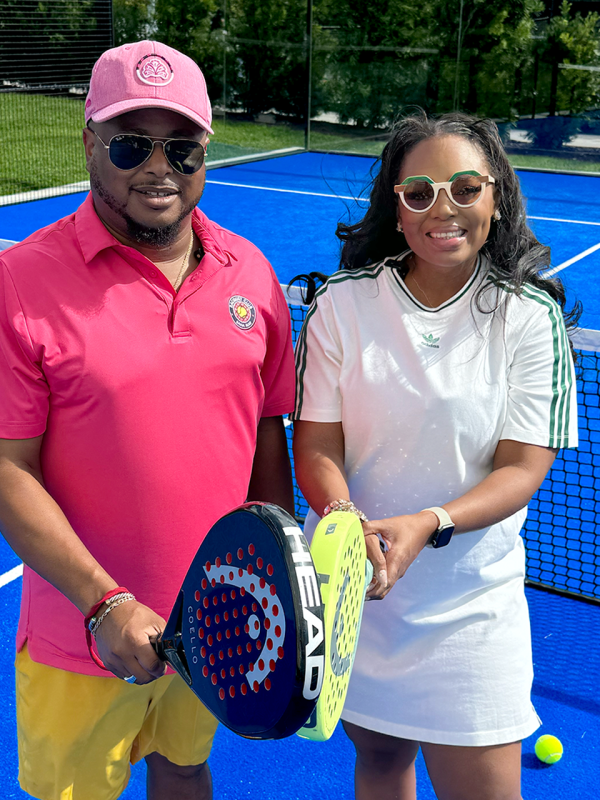 A man and a woman hold sports paddles together with sunglasses on.