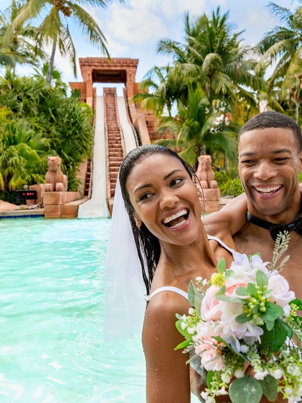 A couple in wedding attire in front of a waterslide.