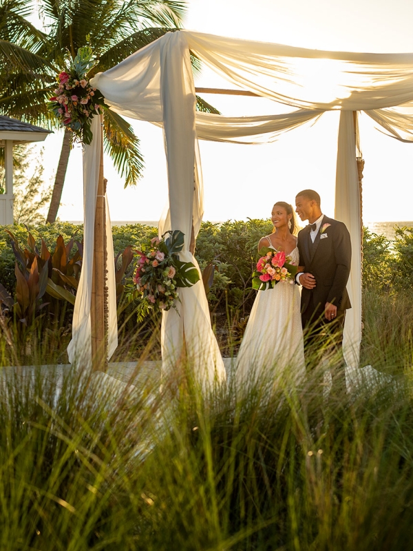Couple getting married under canopy outside in the grass