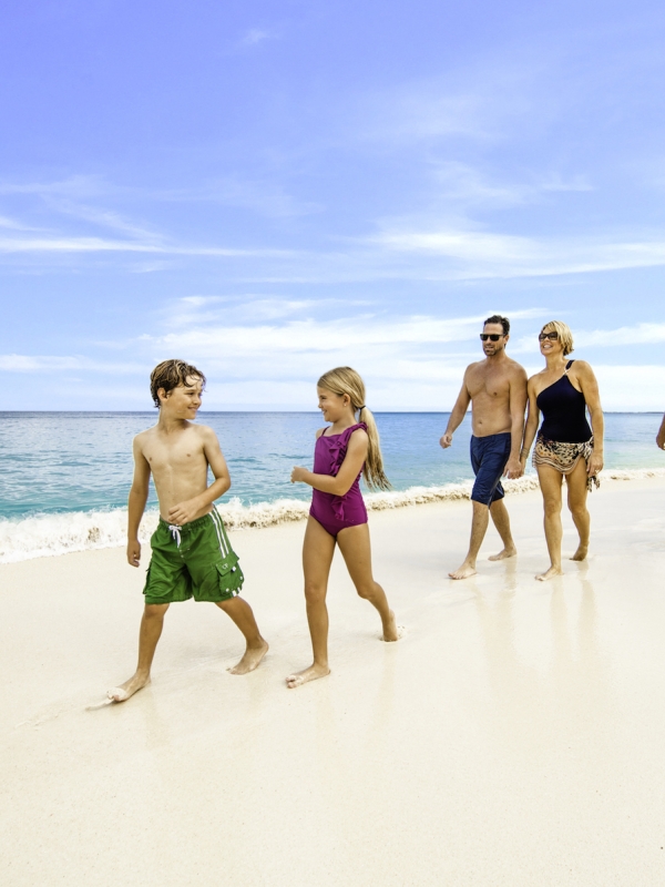 Two children, their parents, and grandparents walk on a Bahamas beach.
