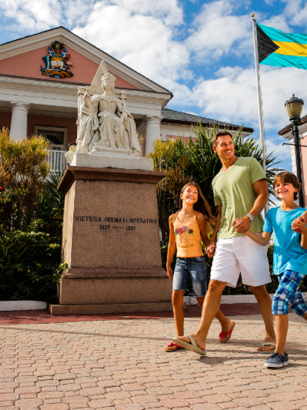 A family of four walks through Parliament Square on a sunny day in Nassau, Bahamas. 