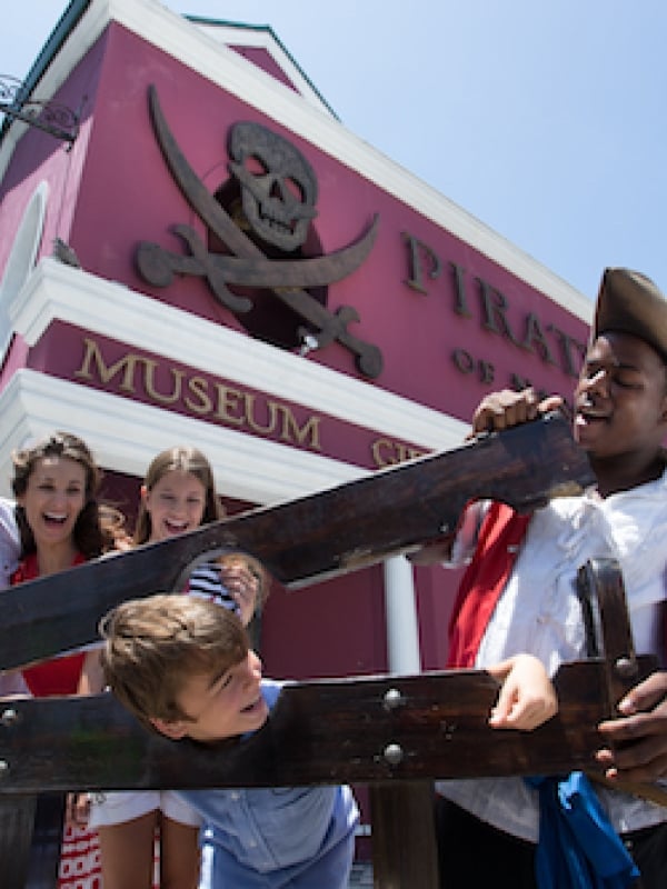 A family and a historical interpreter have fun outside the Pirate of Nassau Museum