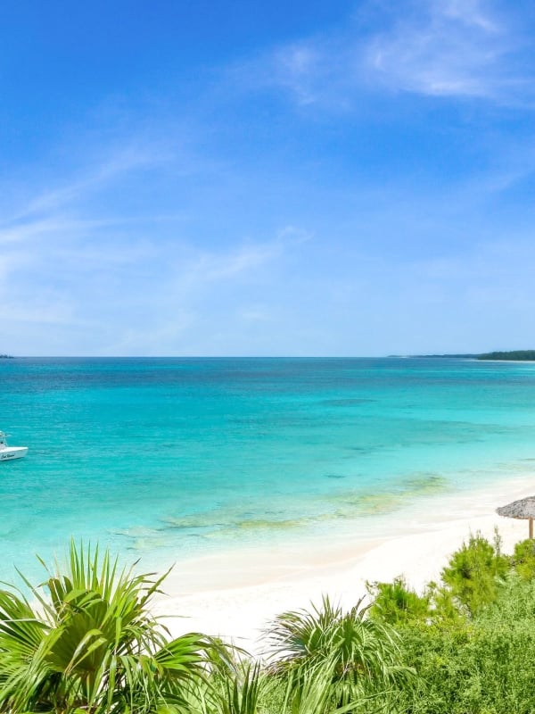 A boat floats in the water with a beach in view.