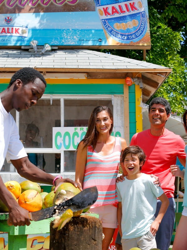 A man cutting a coconut for a family.