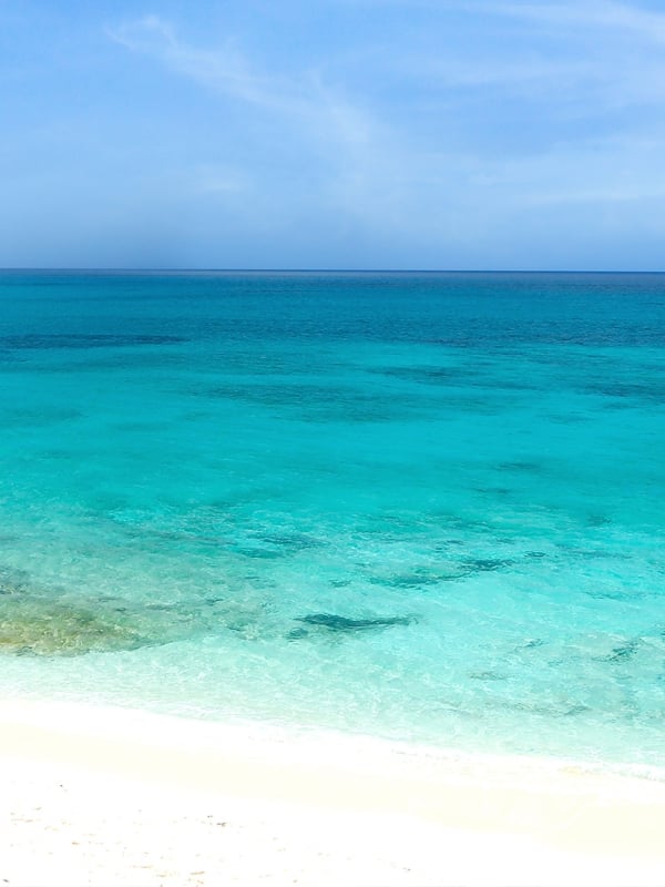 A small motor boat sailing through clear turquoise waters on a beautiful day.