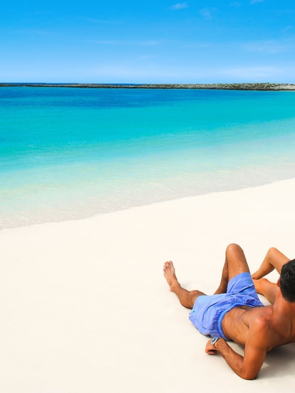 A couple lounge together in the sun on a Nassau Paradise Island beach