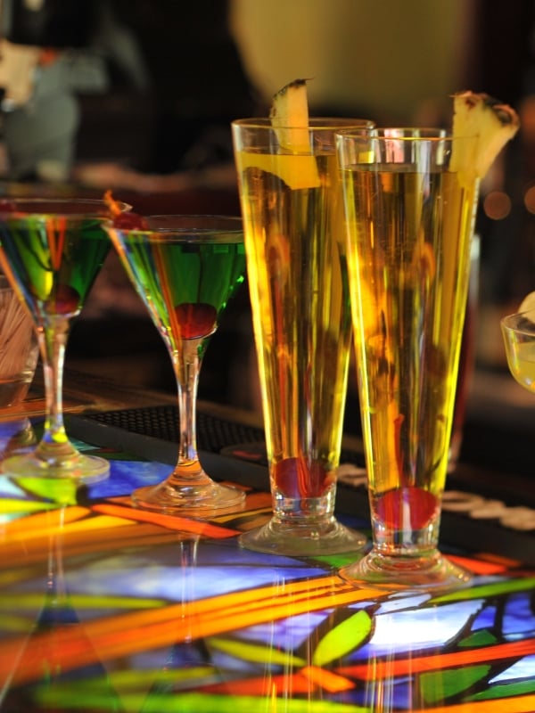 A row of tropical cocktails sits on a colorful bar.