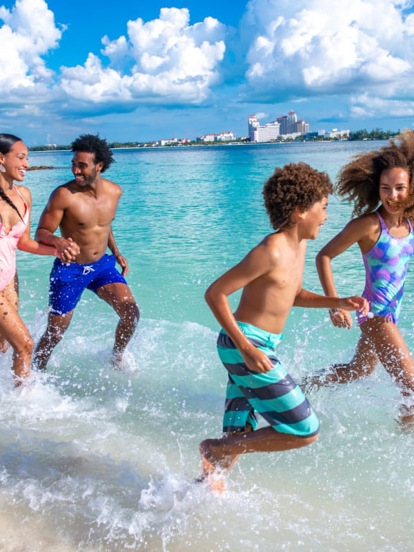 A family of fun splashes in the waves on a Bahamas beach.