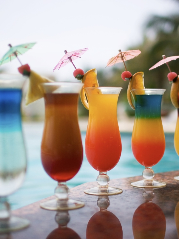 A row of colorful tropical drinks by a pool
