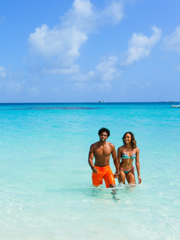 A couple walking in the ocean on Rose Island