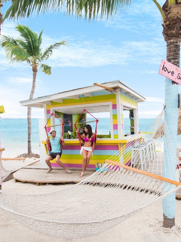 A couple sits on a hammock at Junkanoo beach in The Bahamas. 