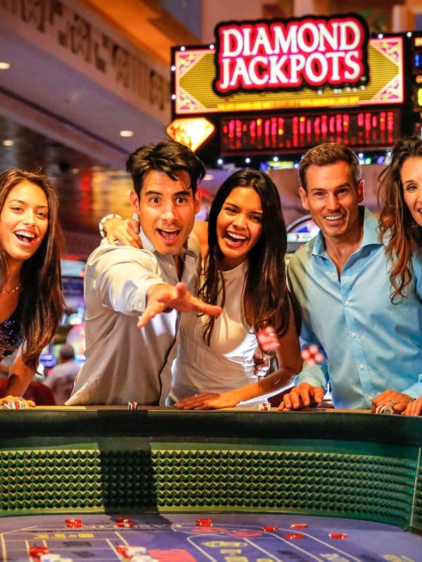 A group of men and women enjoying a game of craps in a casino.