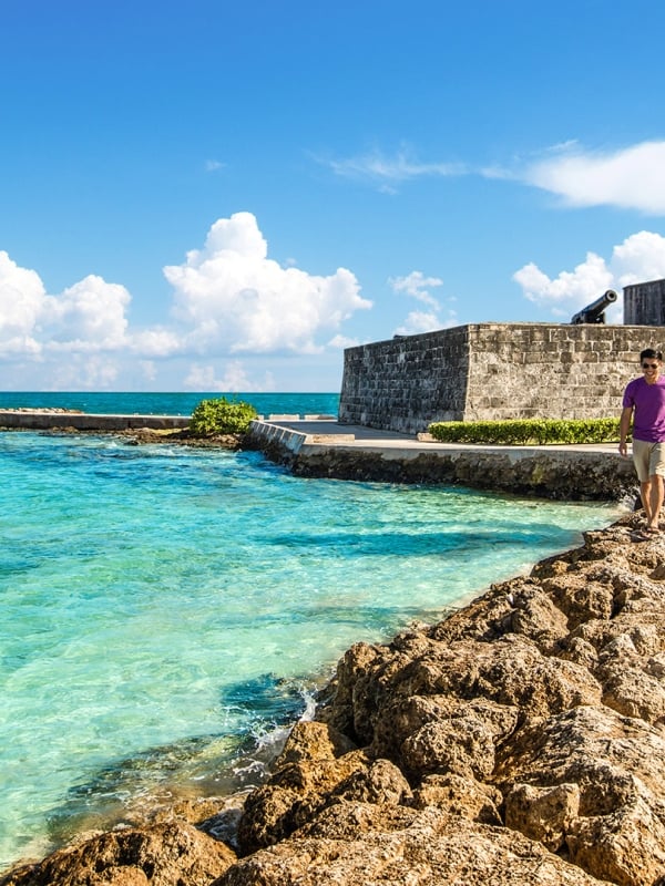 A couple walking hand-in-hand along the rocks at Fort Montague, Bahamas.