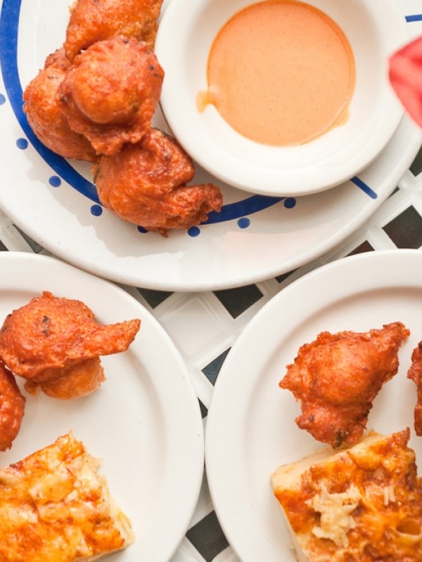 Bahamian Conch fritters set atop white plates.