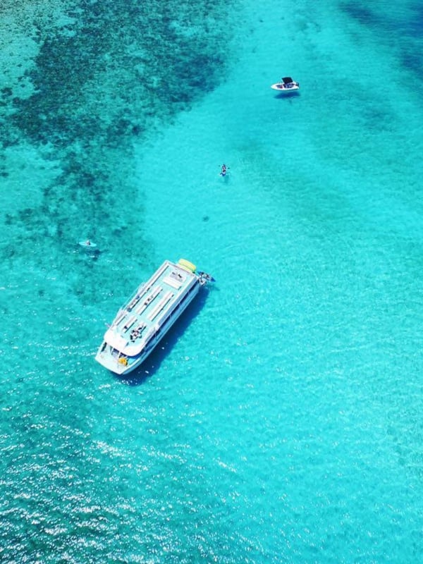 An aerial view of boats in crystal clear tropical waters.