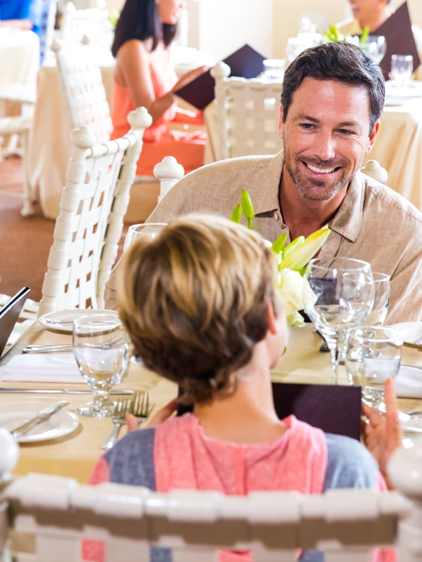 A family of four have dinner in a sunny outdoor restaurant.