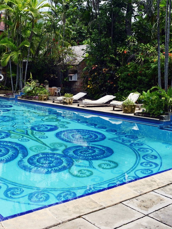 A pool with intricate details surrounded by green trees.