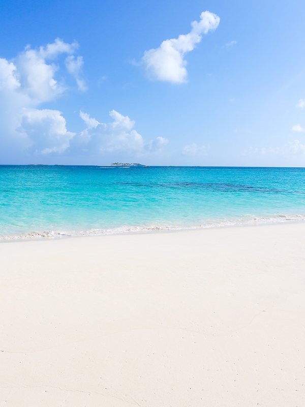 Sandy beach with blue water and boat in the ocean